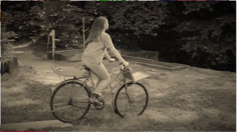 Schwarz-weiss-Bild von M&auml;dchen auf Fahrrad.